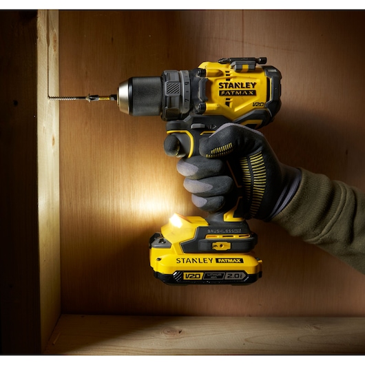 Stanley SFMCD725D2K drill driver in use, close-up, yellow and black, with LED light, photography.