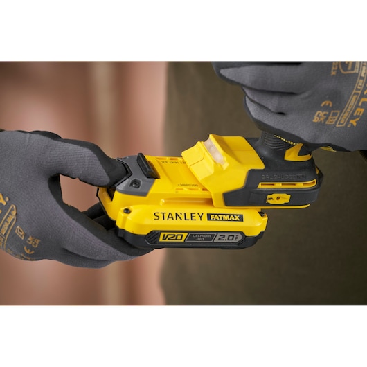 STANLEY SFMCD725D2K cordless drill close-up showing V20 lithium-ion battery held by gloved hands.