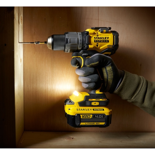 STANLEY SFMCD726B cordless drill in use, side angle, yellow and black design, drilling into wood.