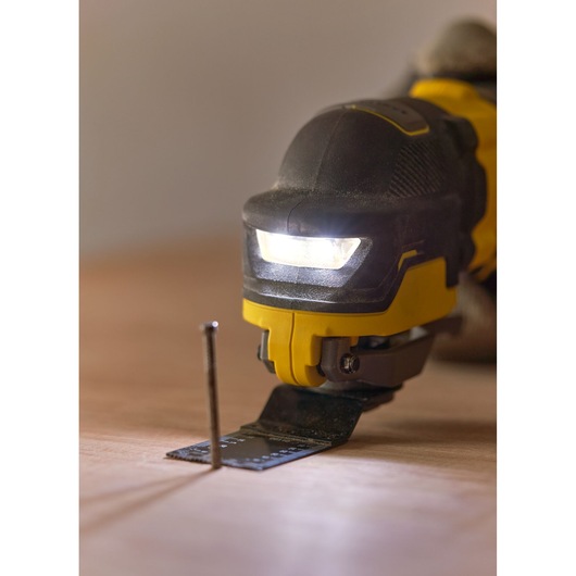 STANLEY SFMCE510B oscillating tool close-up with LED light on, cutting near a nail on wood.