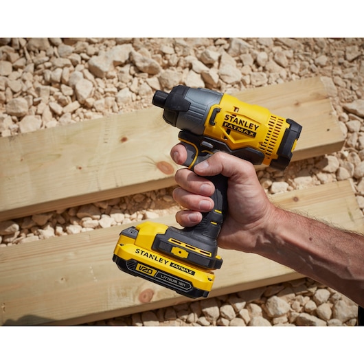 Stanley SFMCF800DM2 cordless impact driver held over wooden boards, yellow and black design.