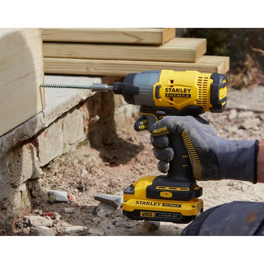 STANLEY SFMCF800DM2 impact driver in use, yellow and black, drilling screw into wooden beam.