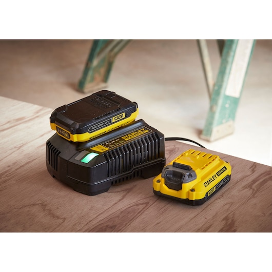 STANLEY SFMCF800DM2 battery charger and battery kit, yellow and black, side angle on wooden surface.