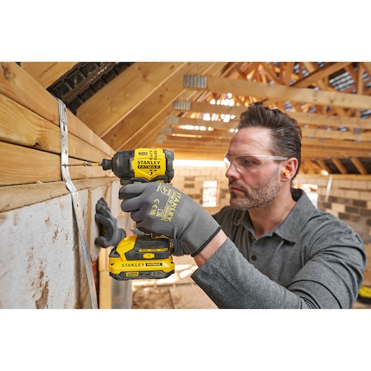 STANLEY SFMCF811B-XJ impact driver in use, yellow and black, drilling into wood frame, construction setting.