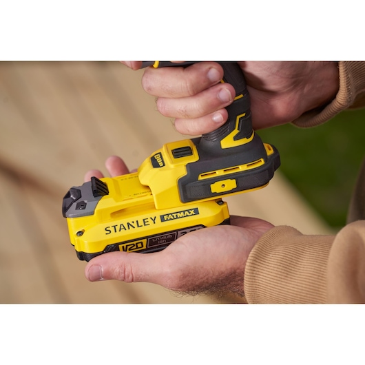 Photo of STANLEY SFMCF820D2K cordless impact driver, yellow and black, held in hands, close-up.
