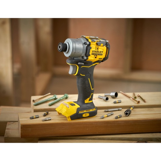 Stanley SFMCF830D2K impact driver, yellow-black, with bits and screws, on wooden planks, front angle.