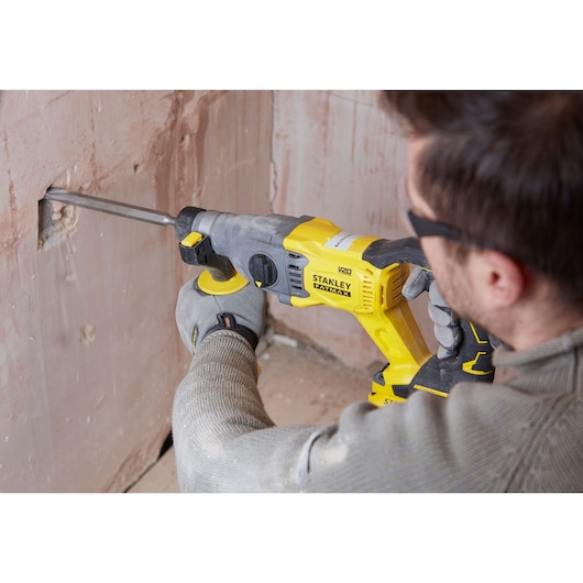 Photo of a person using a STANLEY SFMCH900B rotary hammer drill on a wall.