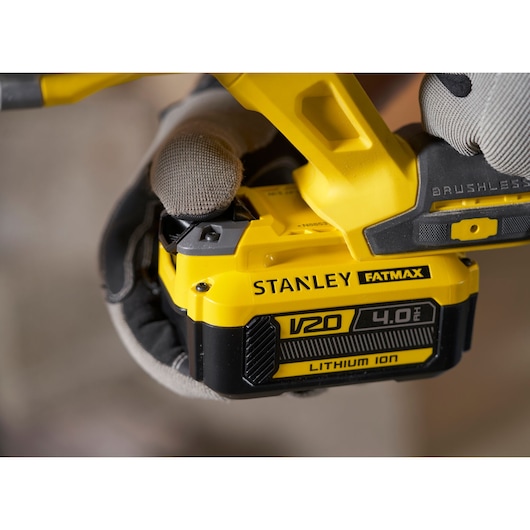 Photo of STANLEY SFMCH900B V20 4.0Ah Lithium Ion battery pack attached to yellow power tool, close-up.