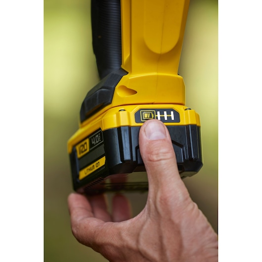 STANLEY SFMCHT855B yellow cordless tool battery being pressed, close-up photography.