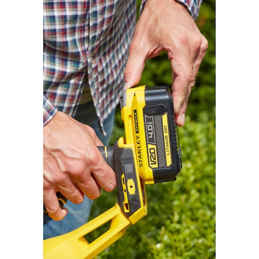 Photo of STANLEY SFMCHT855M1 V20 4.0Ah Lithium-Ion battery being inserted into yellow tool outdoors.