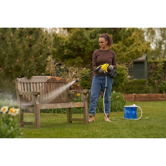 STANLEY SFMCPC93M1 pressure washer in use cleaning a wooden bench outdoors, garden setting.