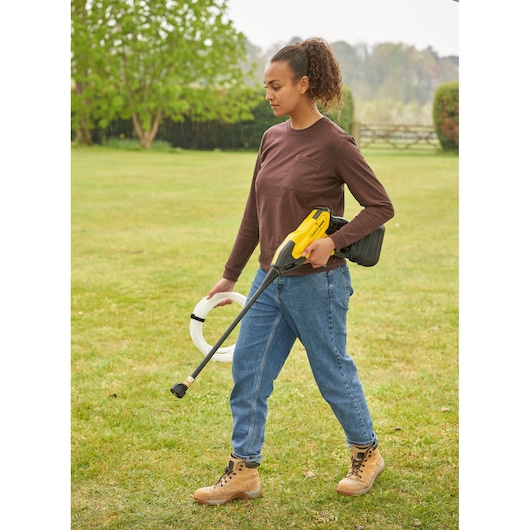 STANLEY SFMCPC93M1 portable power cleaner held by person standing on grass, carrying hose outdoors.