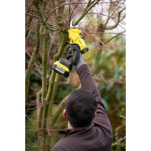 Photo of STANLEY SFMCPP32B cordless pruner used to cut tree branches outdoors.