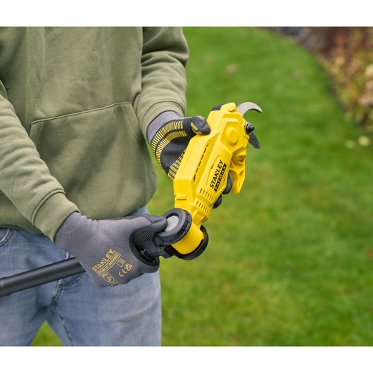 Photo of STANLEY SFMCPP632D1 cordless pruner being held outdoors, yellow body, worker wearing gray gloves.