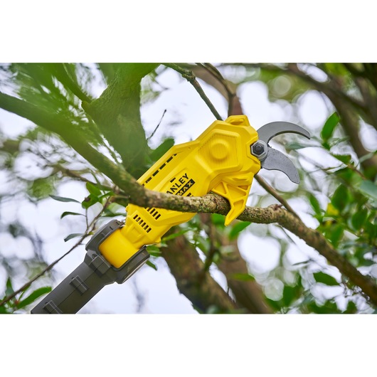 STANLEY SFMCPP632D1 yellow cordless pruning shears cutting a tree branch outdoors.