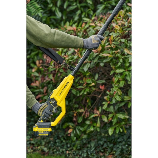STANLEY SFMCPS720M1 pole saw shown in use outdoors, yellow and black design, close-up side view.
