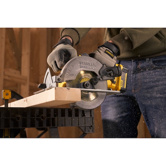 Stanley SFMCS500M1S circular saw cutting timber, close-up, with sawdust flying in workshop.