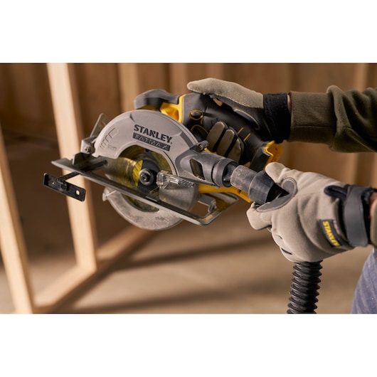 STANLEY SFMCS500M1S circular saw used by gloved hands, indoor construction setting, side view.