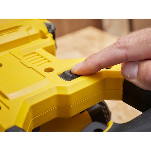 STANLEY SFMCS701M2 saw close-up, finger pressing black power button on yellow handle.
