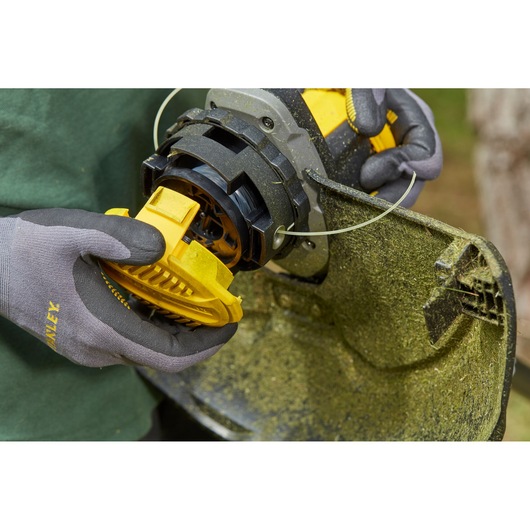 Photo of STANLEY SFMCSTB963B string trimmer spool being installed, close-up outdoor view.