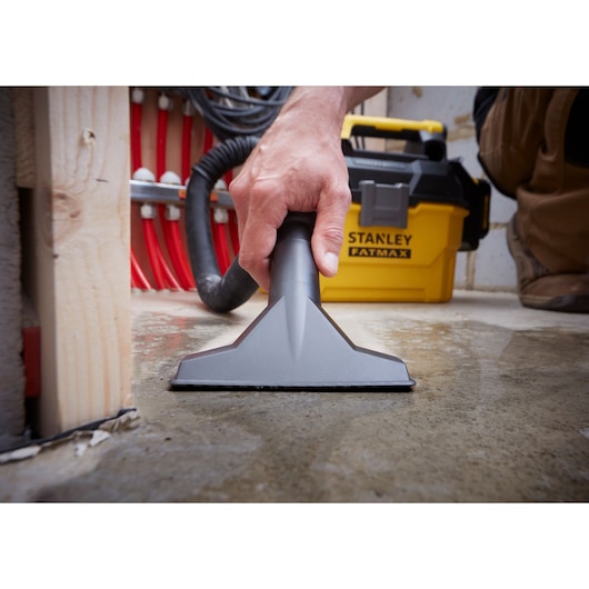 STANLEY SFMCV002B wet and dry vacuum used on a wet floor, close-up of nozzle and yellow vacuum unit.