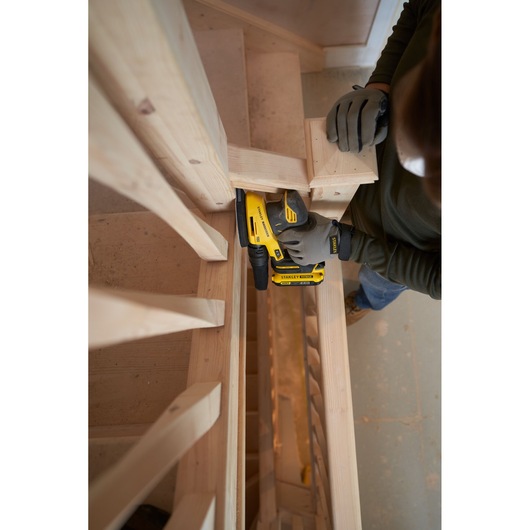 STANLEY SFMCW221B sander used on wooden stairs, close-up angle, operator wearing gloves.