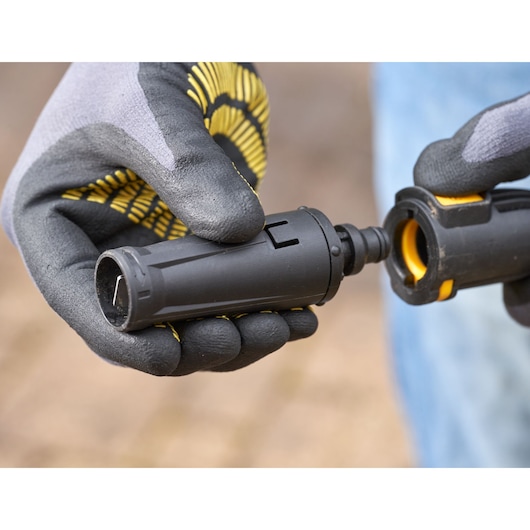 Photo of STANLEY SFMPW2400 connector being assembled, black with yellow accents, gloved hands visible.