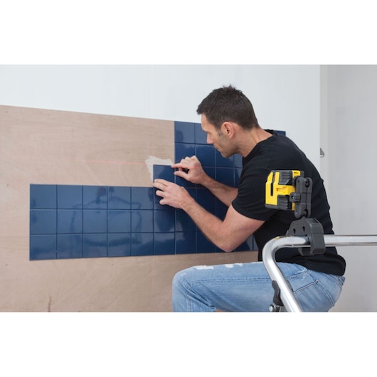 STANLEY STHT1-77341 photography of yellow laser level mounted on metal frame aligning blue tiles on wall.