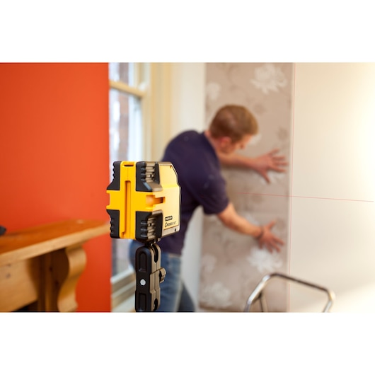 STANLEY STHT1-77341 laser level photography, yellow tool with black accents used for wall alignment.
