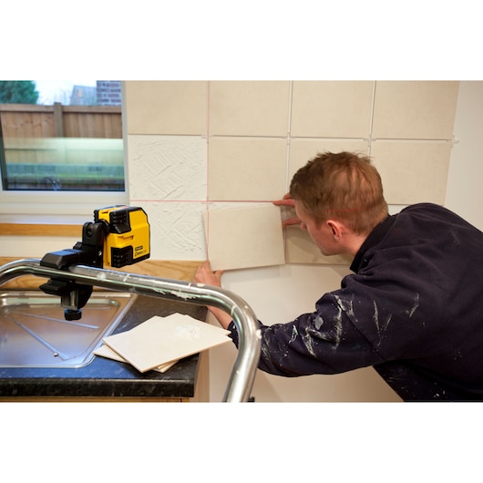 STANLEY STHT1-77341 photography of tile installation using yellow laser level in kitchen setting.