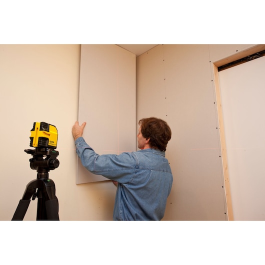 STANLEY STHT1-77341 laser level on tripod used for wall alignment, interior installation scene.