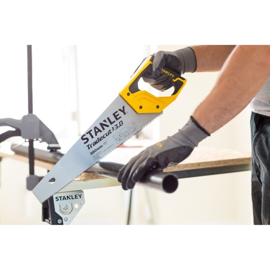 STANLEY STHT20348-0 hand saw with yellow handle cutting pipe, close-up action shot.