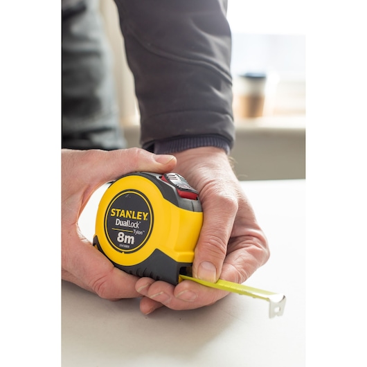 Photo of STANLEY STHT36809-0 measuring tape held in hand, yellow and black casing, 8m length visible.