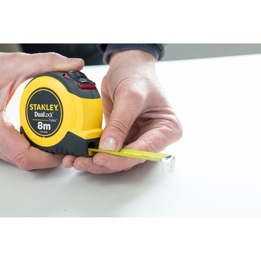 Photo of STANLEY STHT36809-0 tape measure, yellow and black, being used to measure on a white surface.