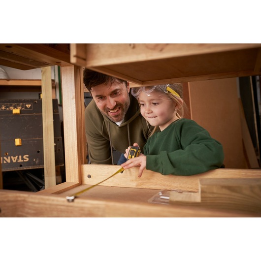 STANLEY TBS001-05-SY tape measure in use during woodworking, close-up angle, photo of product held by person.