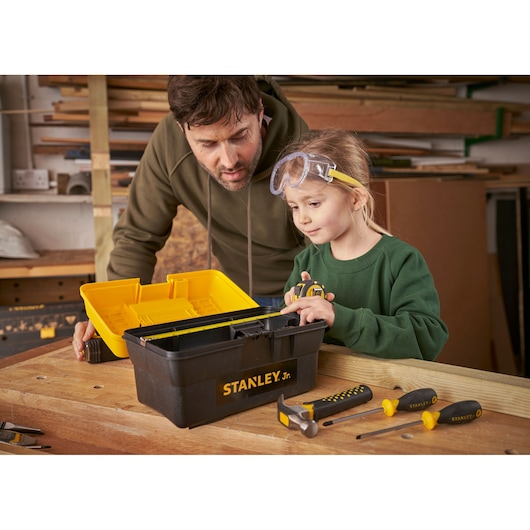 Photo of STANLEY TBS001-05-SY black and yellow tool box with children’s tools on a workbench.