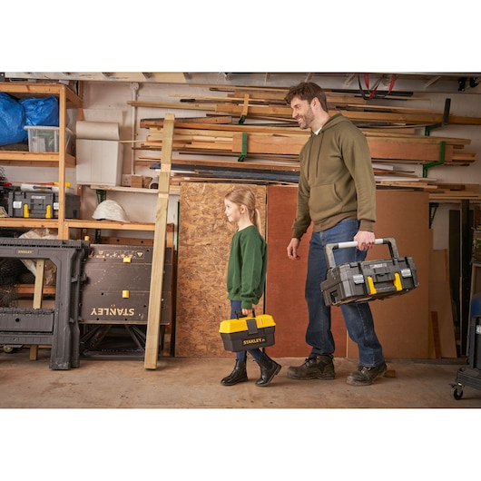 STANLEY TBS001-05-SY toolbox photography, man and child carrying toolboxes in workshop setting.