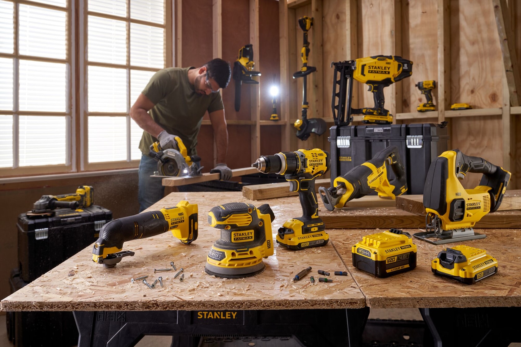 Stanley SFMCF820 power tools on workbench in workshop, various tools and batteries visible.